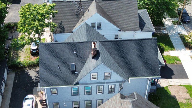 New roof installation on a residential build, showing decking, underlayment, and the first courses of shingles