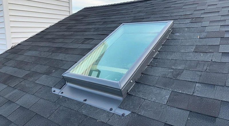 Skylight installed on a pitched shingle roof with step and counter flashing sealed around the curb